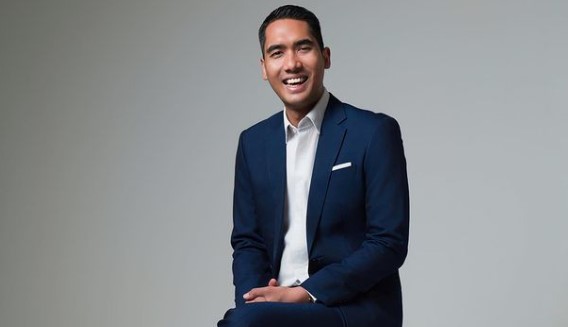 Two women sitting at a modern table talking with a city view behind them.